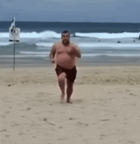 a shirtless man is running on a beach near the ocean .