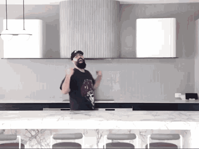 a man with a beard is dancing in a kitchen while wearing a black shirt with a skull on it .
