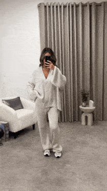 a woman taking a picture of herself in a living room with a chair