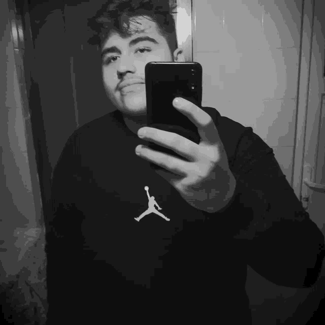 a man is taking a selfie with his phone and his shirt says air jordan