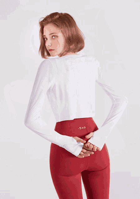 a woman wearing red pants and a white shirt