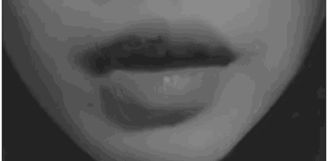 a black and white photo of a woman 's mouth with a shadow on it .