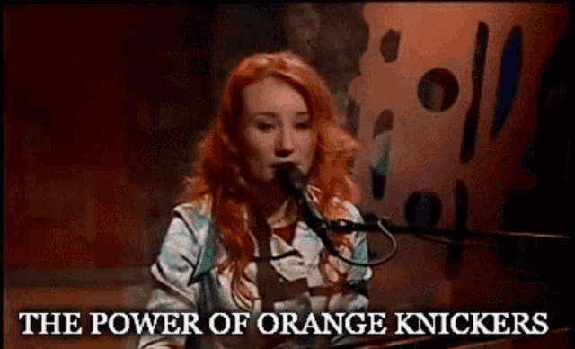a woman singing into a microphone with the words " the power of orange knickers " next to her