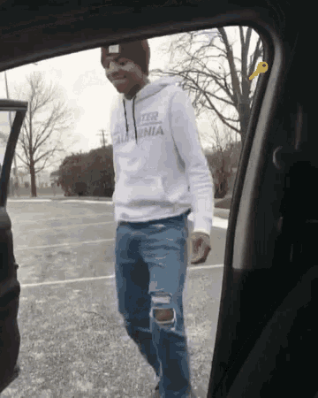 a man wearing a hoodie that says california walking out of a car