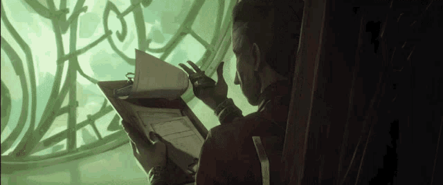 a man in a red jacket is sitting in front of a window reading a book