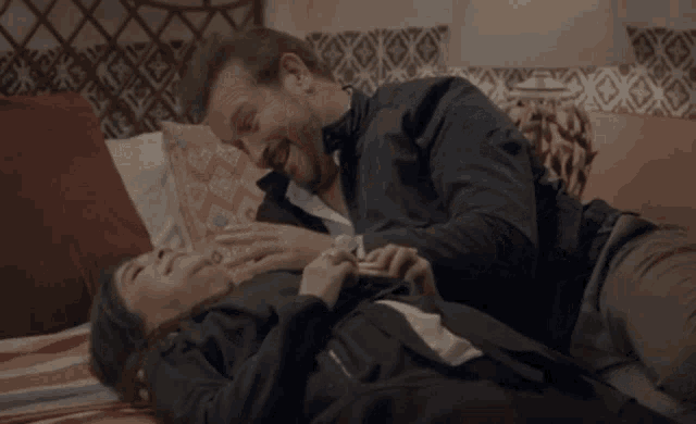 a man is laying on a bed laughing while holding his feet