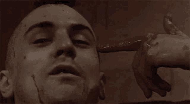 a close up of a man 's face with blood on it and a hand pointing at his face .