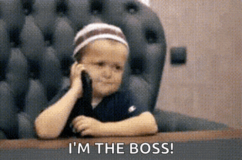 a little boy is sitting at a table talking on a cell phone .