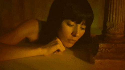 a woman with long black hair is laying on the floor with her head on the floor .