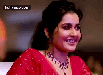 a close up of a woman wearing a red dress and a necklace smiling .