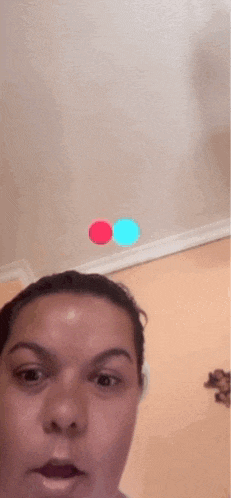 a woman is taking a selfie in front of a wall with a red circle on it .