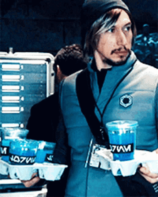 a man carrying a tray of cups with the letters s7mv on them