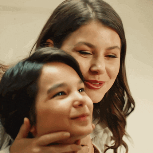 a woman is holding a child 's neck and they are smiling