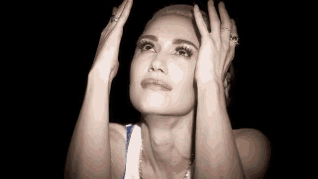 a woman with her hands on her head is looking up at the sky .