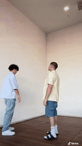 two men standing next to each other in an empty room with tik tok written on the bottom