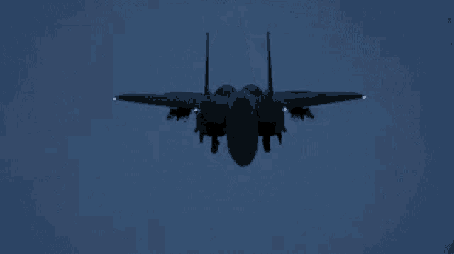 a fighter jet is flying through the air at night .