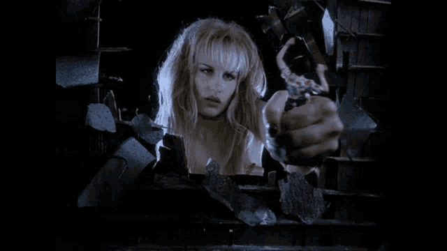 a woman is holding a gun behind a broken window