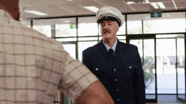 a man in a police uniform is talking to another man in a plaid shirt