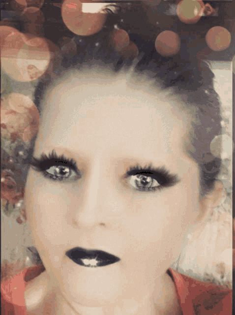 a close up of a woman 's face with long eyelashes and black lipstick