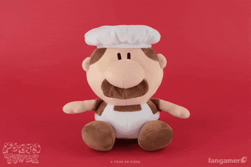 a stuffed animal with a chef 's hat and apron is sitting on a red table