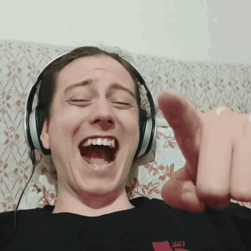 a man wearing headphones is pointing at the camera with his mouth open