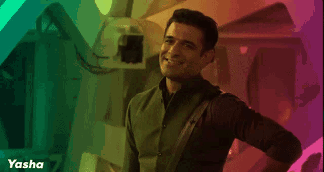 a man is standing in front of a rainbow colored background with the name yasha on the bottom
