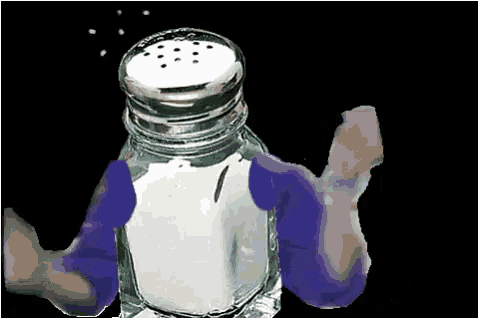 a salt shaker is being held by a person in purple gloves