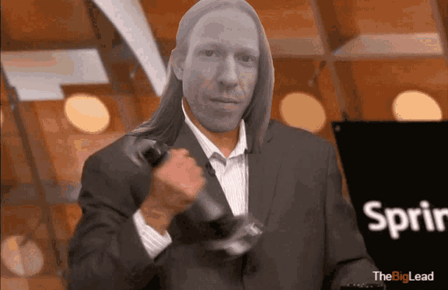 a man in a suit is holding a dumbbell in front of a sign that says ' sprint '
