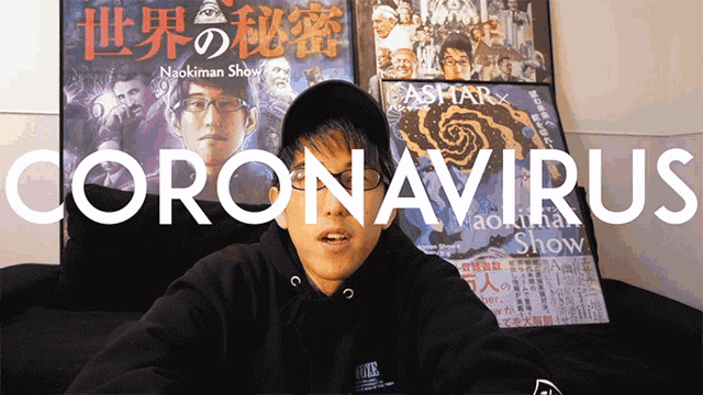 a man is sitting in front of a sign that says coronavirus