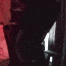 a blurry picture of a person standing in a dark room with a red light behind them .