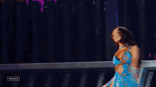a woman in a blue dress is dancing on a stage with purple lights behind her ..