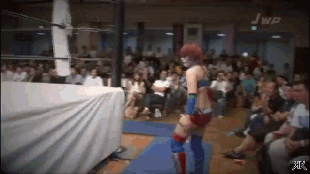 a woman is wrestling in a ring in front of a crowd of people .