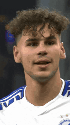 a young man with curly hair is wearing a blue and white jersey that says ' copenhagen ' on it
