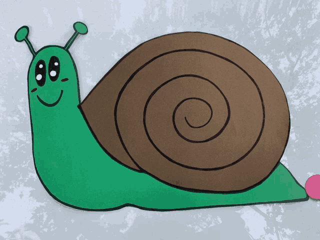 a paper snail with a brown shell and a green face