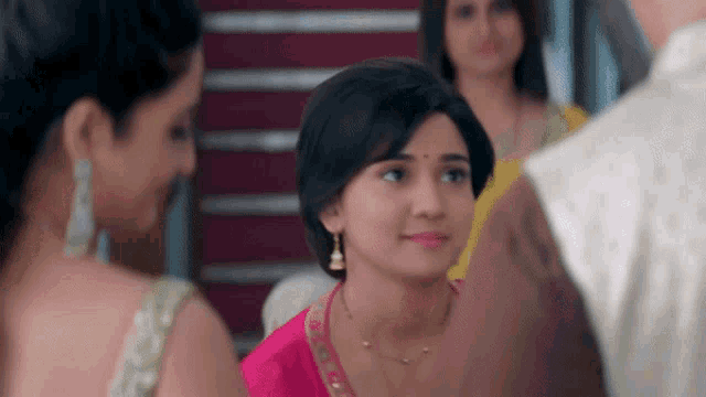 a woman in a pink saree is smiling while standing next to another woman