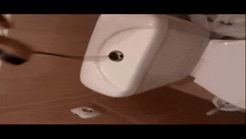 a white toilet is sitting on a brown tiled floor in a bathroom