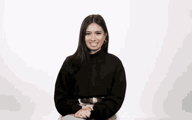 a woman wearing a black sweater and jeans is smiling for the camera