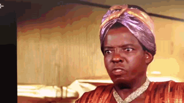 a man wearing a turban and a necklace is making a face