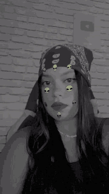 a woman wearing a bandana with aliens on her face is taking a selfie .