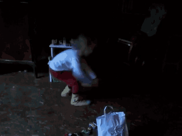 a little girl squatting down in a dark room next to a bag that says cosa