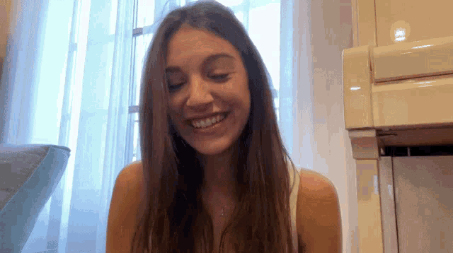 a woman with long brown hair is smiling in front of a piano