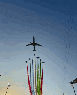 a plane is flying over a row of planes with smoke trails