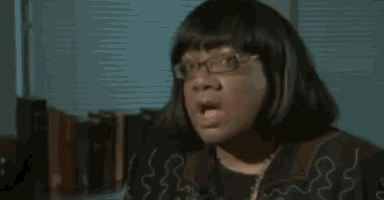 a woman wearing glasses and a black sweater is talking