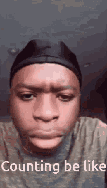 a young man wearing a hat and a t-shirt is making a funny face and says counting be like .
