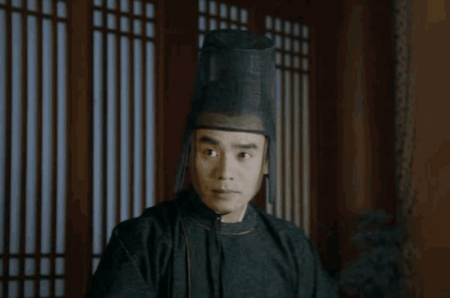 a man wearing a black hat is standing in a room