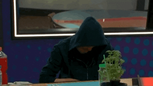 a man wearing a hooded jacket is sitting at a table