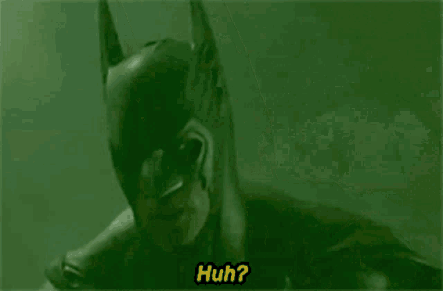 a close up of a man in a batman costume saying huh .
