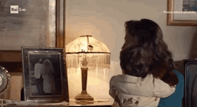 a woman is holding a child in her arms in front of a lamp and a picture .