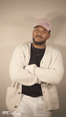 a man wearing a white cardigan and a pink hat with the letter mc on it