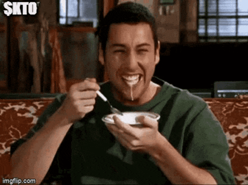 a man is eating food with a spoon and smiling .
